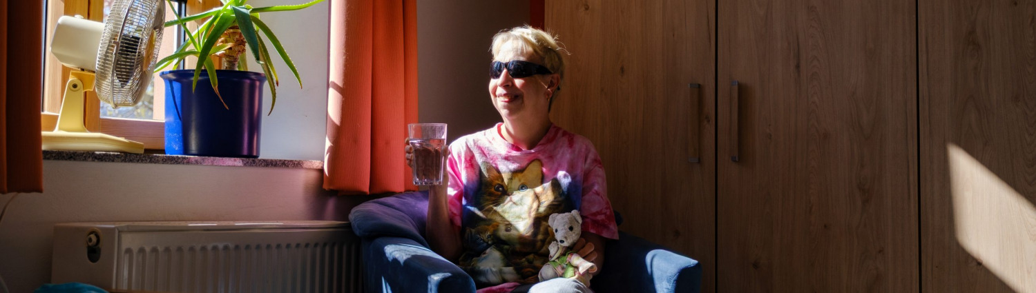 Sonja sitzt im Wohnheim der Lebenshilfe Bad Dürkheim am Fenster ihres Zimmers